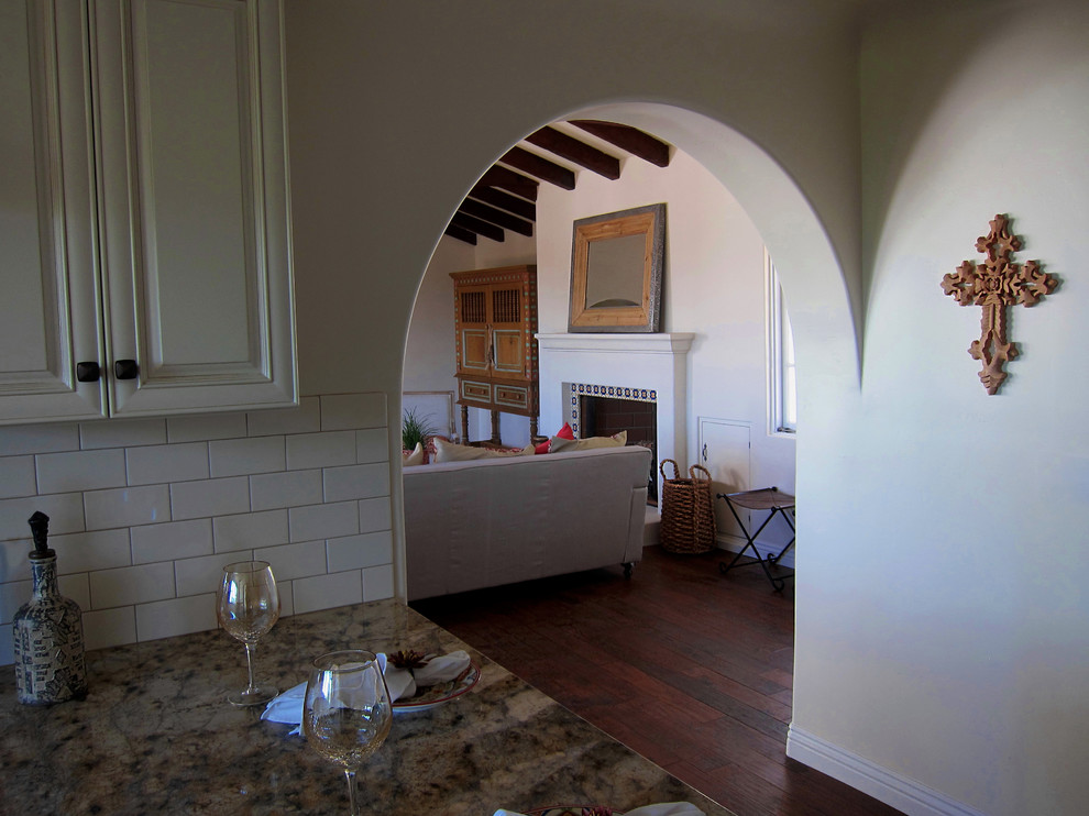 サンタバーバラにある高級な小さな地中海スタイルのおしゃれな独立型リビング (白い壁、無垢フローリング、標準型暖炉、テレビなし、タイルの暖炉まわり、茶色い床) の写真