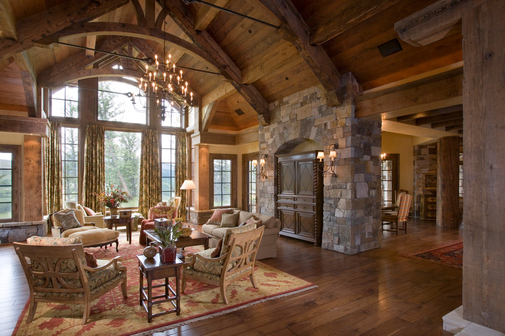 Idées déco pour un salon montagne ouvert avec un manteau de cheminée en pierre et un sol en bois brun.