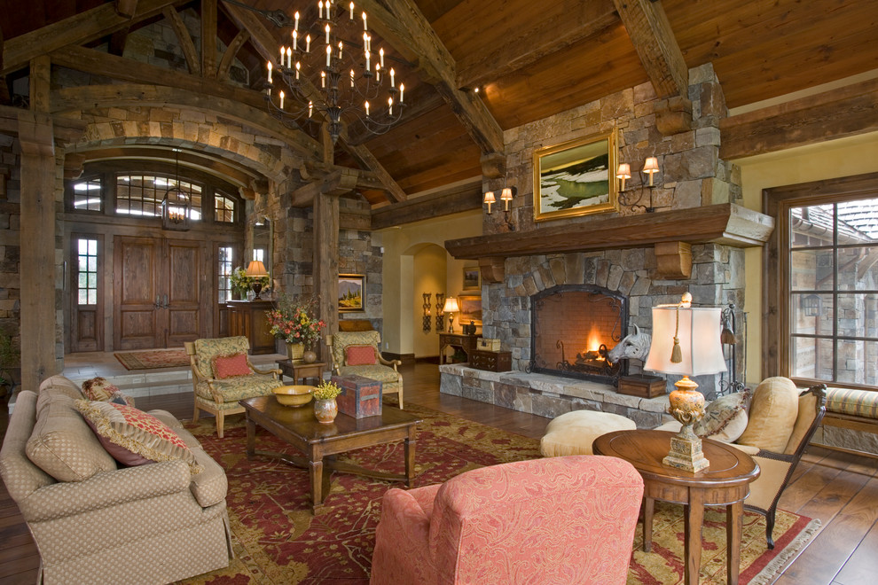 Aménagement d'un salon montagne ouvert avec un manteau de cheminée en pierre, un sol en bois brun et une cheminée standard.