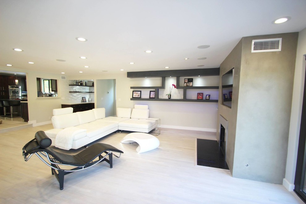 This is an example of a large modern living room in Los Angeles with white walls, a built-in media unit and a standard fireplace.