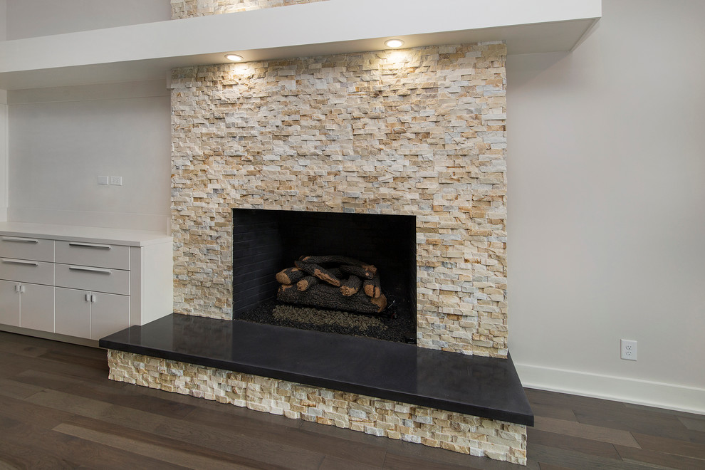 Example of a large minimalist open concept medium tone wood floor living room design in Charlotte with white walls, a standard fireplace, a stone fireplace and a media wall