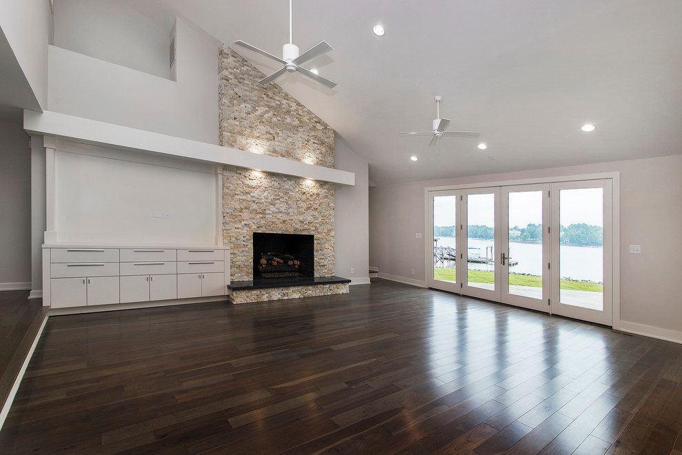 Minimalist medium tone wood floor living room photo in Charlotte with white walls, a standard fireplace, a stone fireplace and a media wall