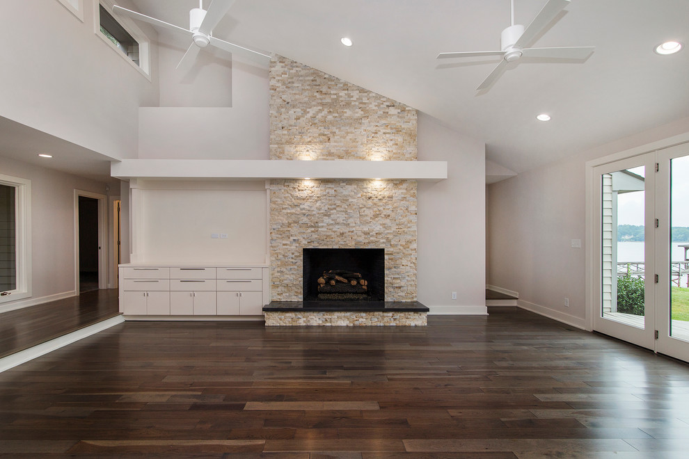 Cette photo montre un grand salon moderne ouvert avec un mur blanc, un sol en bois brun, une cheminée standard, un manteau de cheminée en pierre et un téléviseur encastré.