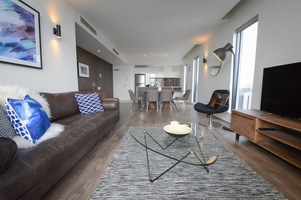 Стильный дизайн: открытая гостиная комната среднего размера в современном стиле с белыми стенами, паркетным полом среднего тона и отдельно стоящим телевизором - последний тренд