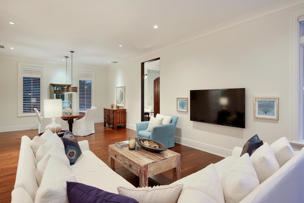 На фото: большая открытая гостиная комната в морском стиле с белыми стенами, паркетным полом среднего тона и отдельно стоящим телевизором без камина