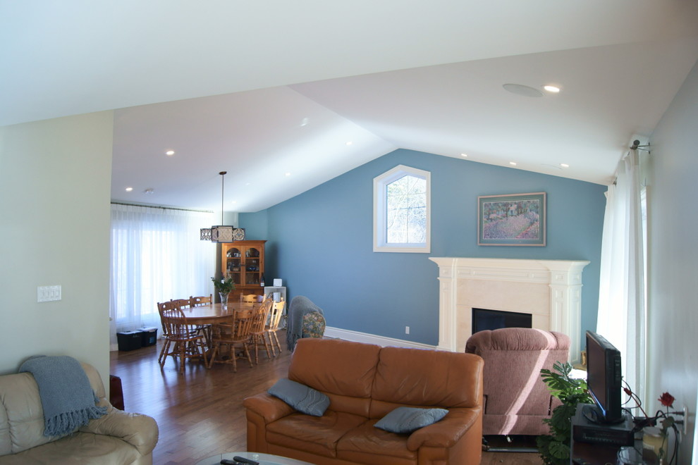 Mittelgroßes, Fernseherloses, Offenes, Repräsentatives Klassisches Wohnzimmer mit blauer Wandfarbe, Kamin, braunem Holzboden und verputzter Kaminumrandung in Ottawa