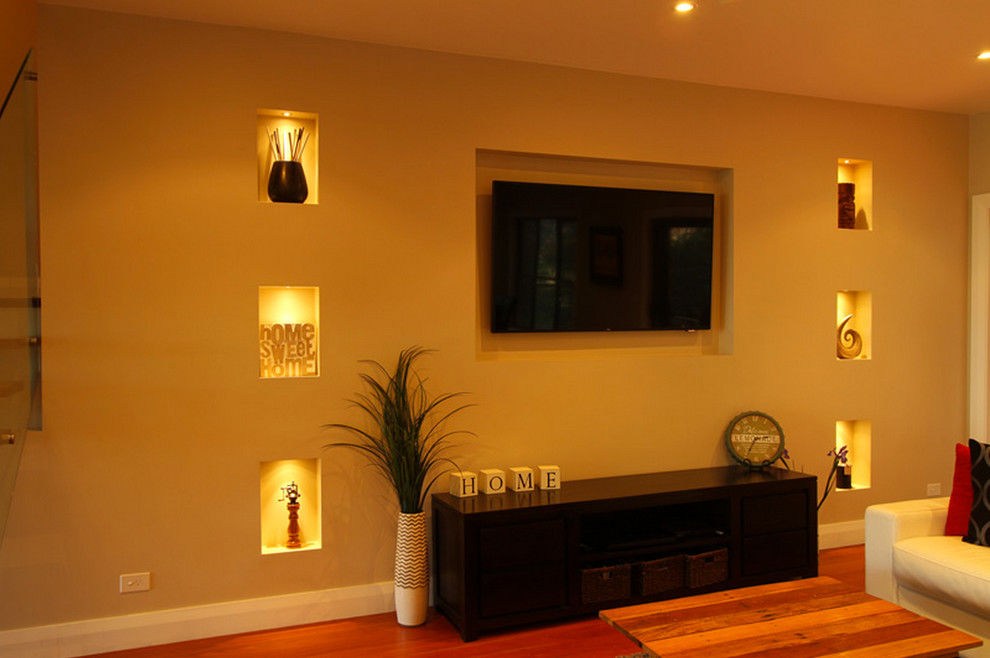 Foto di un soggiorno minimal aperto con pareti beige, pavimento in legno massello medio e TV a parete