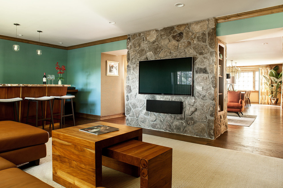 Пример оригинального дизайна: открытая гостиная комната среднего размера в стиле ретро с домашним баром, зелеными стенами, паркетным полом среднего тона, фасадом камина из камня и телевизором на стене