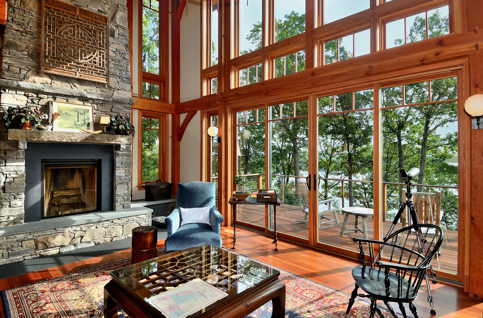 Inspiration pour un salon traditionnel ouvert avec un sol en bois brun, une cheminée standard, un manteau de cheminée en pierre et un mur beige.