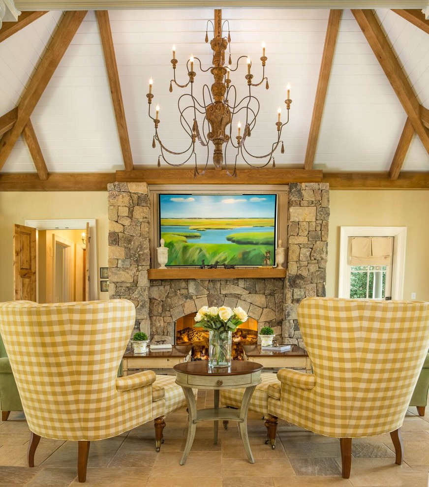 На фото: гостиная комната в стиле кантри с желтыми стенами, стандартным камином и фасадом камина из камня