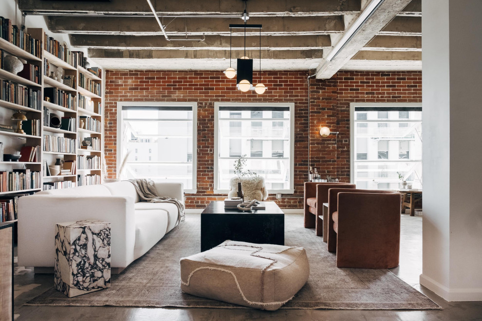 Example of a huge urban open concept concrete floor, gray floor, exposed beam and brick wall living room library design in Other with red walls and no fireplace