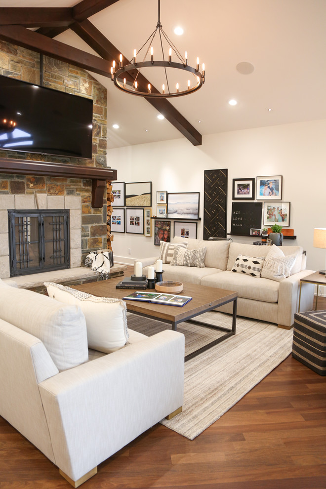 Huge country open concept medium tone wood floor and brown floor living room photo in Vancouver with white walls, a two-sided fireplace, a stone fireplace and a wall-mounted tv