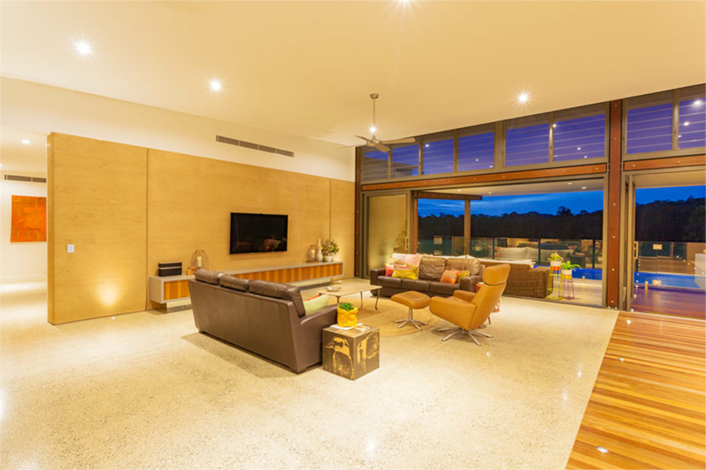 This is an example of an expansive contemporary open plan living room in Brisbane with beige walls, concrete flooring, a standard fireplace, a stone fireplace surround and a wall mounted tv.