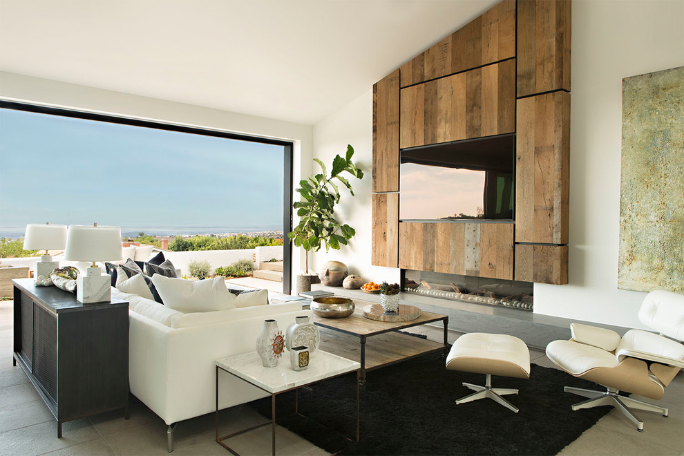 Источник вдохновения для домашнего уюта: открытая гостиная комната в современном стиле с белыми стенами, горизонтальным камином, фасадом камина из дерева, телевизором на стене и серым полом