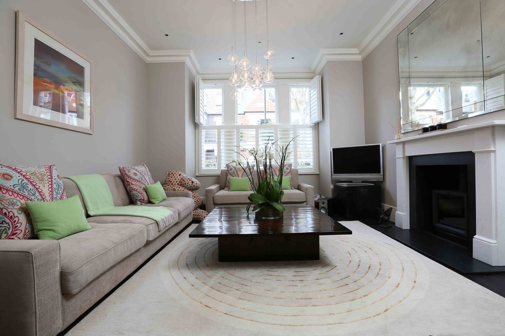 This is an example of a contemporary enclosed living room in London with grey walls, carpet, a standard fireplace, a plastered fireplace surround, a freestanding tv and beige floors.