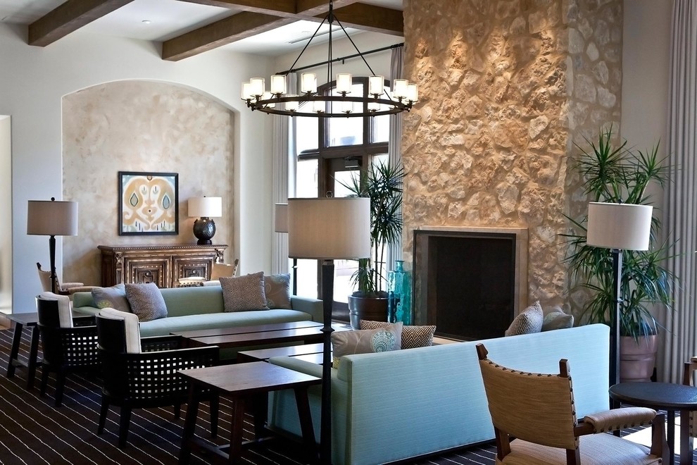 Großes, Offenes Mediterranes Wohnzimmer mit beiger Wandfarbe, Teppichboden, Kamin und Kaminumrandung aus Stein in Phoenix