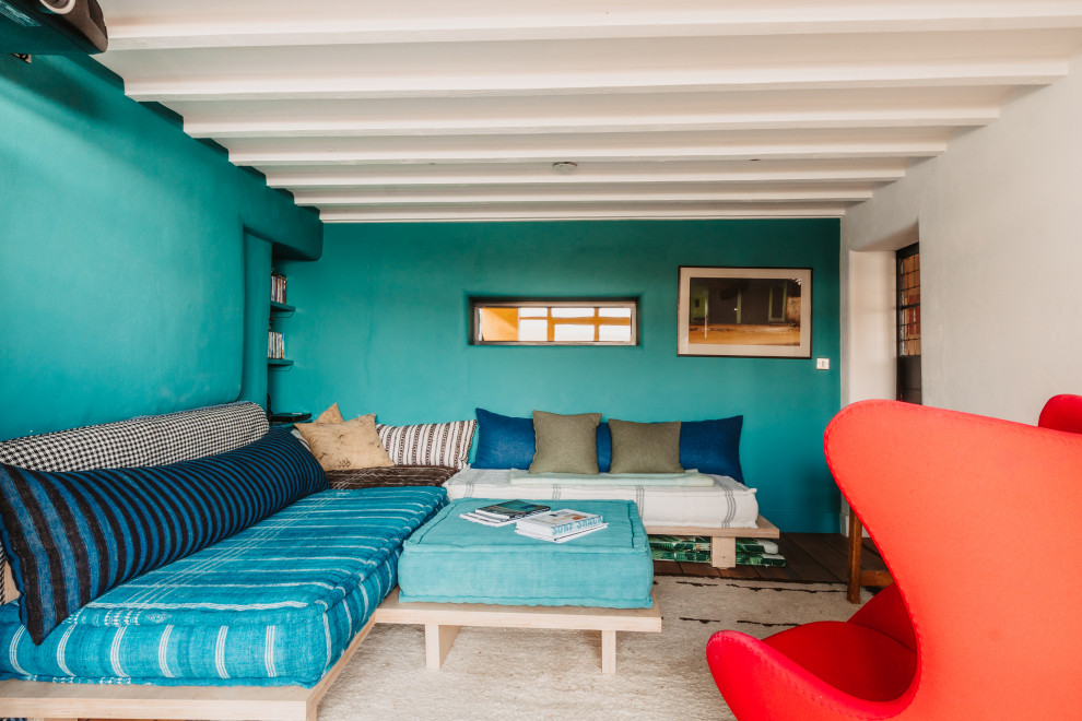 Ejemplo de salón cerrado costero de tamaño medio con paredes azules, suelo de madera oscura, suelo marrón y vigas vistas