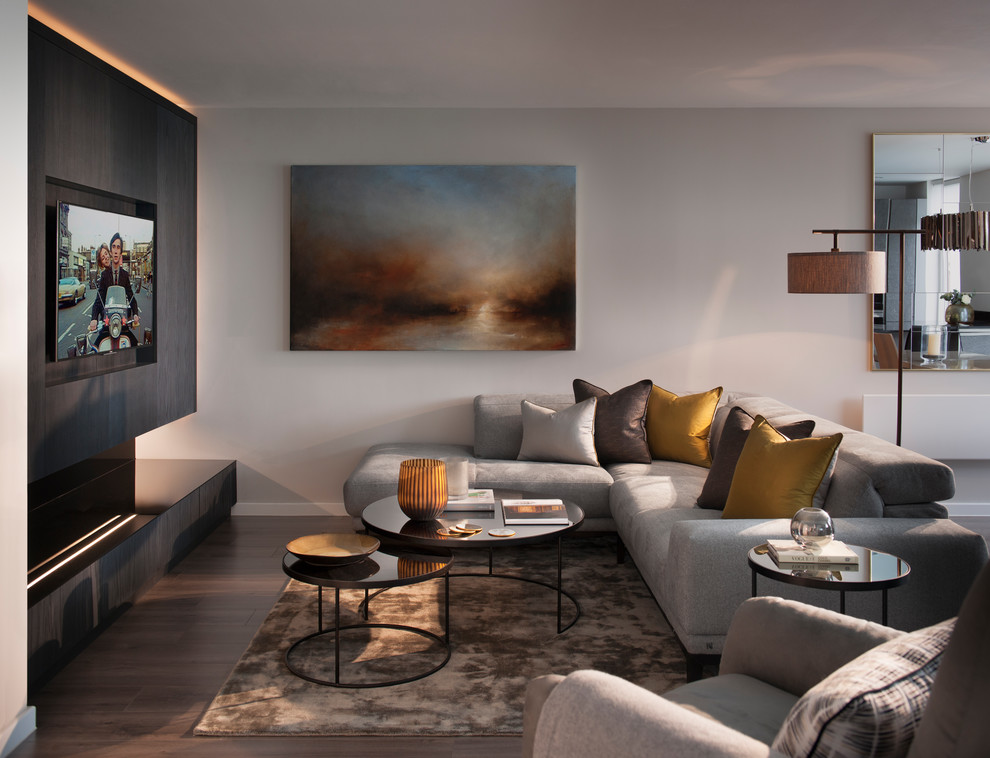Inspiration pour un salon design de taille moyenne et fermé avec un mur gris, parquet foncé, un téléviseur fixé au mur et un sol marron.