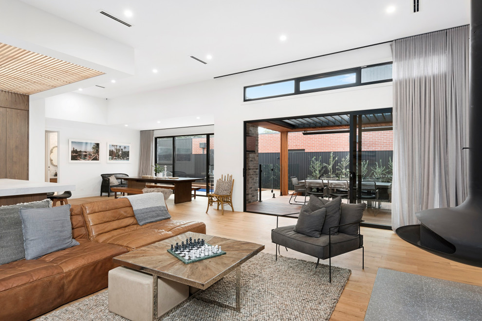 Großes Maritimes Wohnzimmer mit weißer Wandfarbe, braunem Holzboden, Hängekamin, gefliester Kaminumrandung und TV-Wand in Melbourne