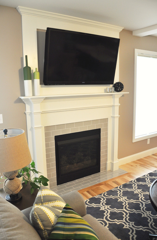 Mittelgroßes, Offenes Klassisches Wohnzimmer mit grauer Wandfarbe, hellem Holzboden, Kamin, gefliester Kaminumrandung und TV-Wand in Burlington
