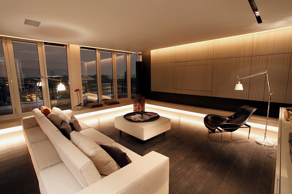 Diseño de salón para visitas abierto actual grande con televisor retractable y suelo de madera oscura