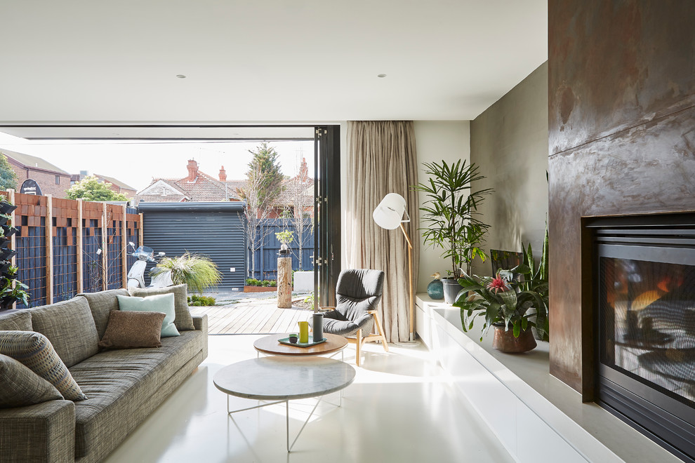 Mittelgroßes, Offenes Modernes Wohnzimmer mit Kamin, Kaminumrandung aus Metall, grauer Wandfarbe und Betonboden in Melbourne