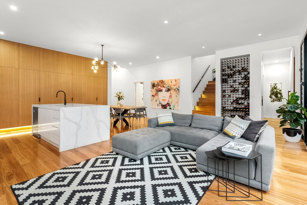 Immagine di un grande soggiorno design aperto con pareti bianche e pavimento in legno massello medio