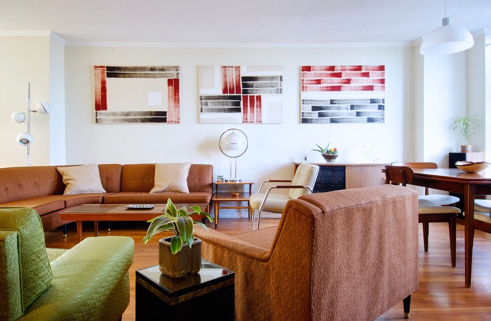 На фото: гостиная комната в стиле ретро с бежевыми стенами и коричневым диваном с