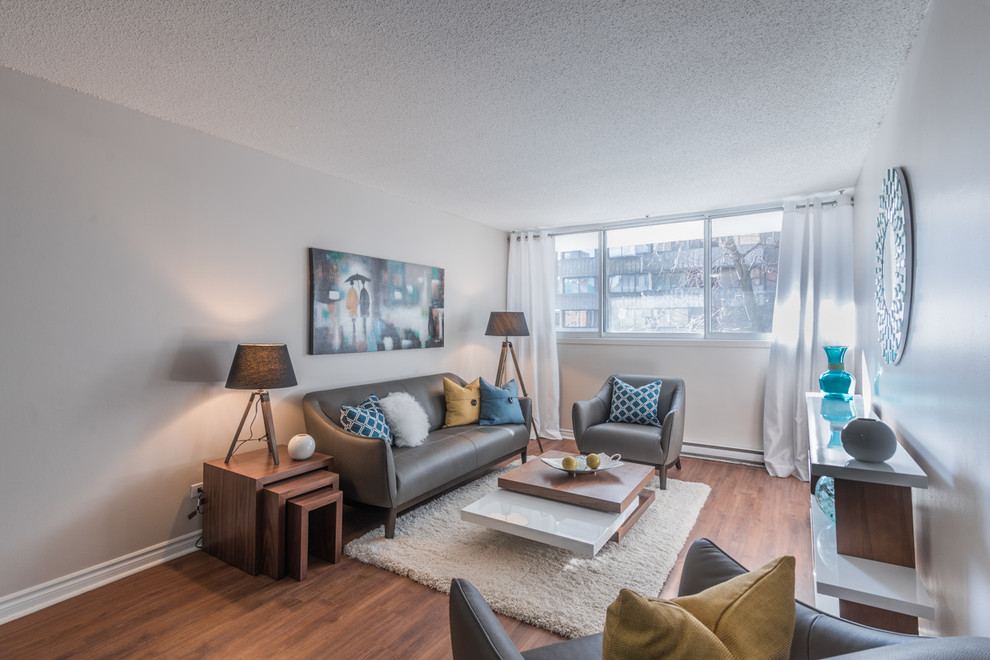 Kleines, Offenes Modernes Wohnzimmer mit weißer Wandfarbe, braunem Holzboden und Multimediawand in Montreal