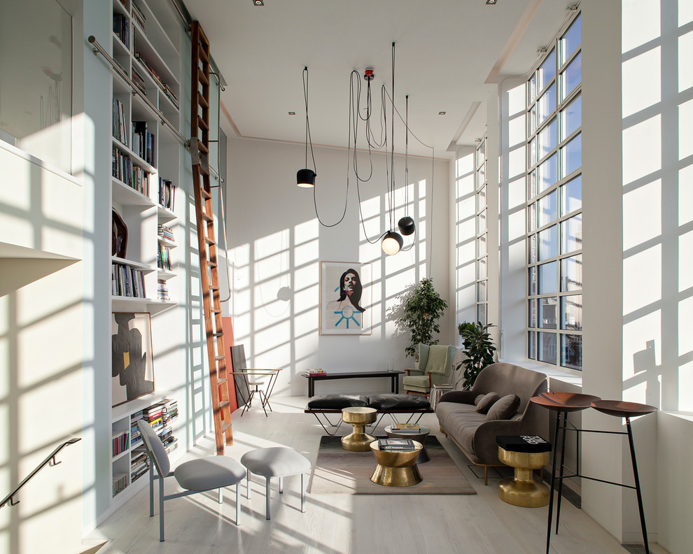 На фото: гостиная комната среднего размера в скандинавском стиле с с книжными шкафами и полками, белыми стенами и светлым паркетным полом без камина с