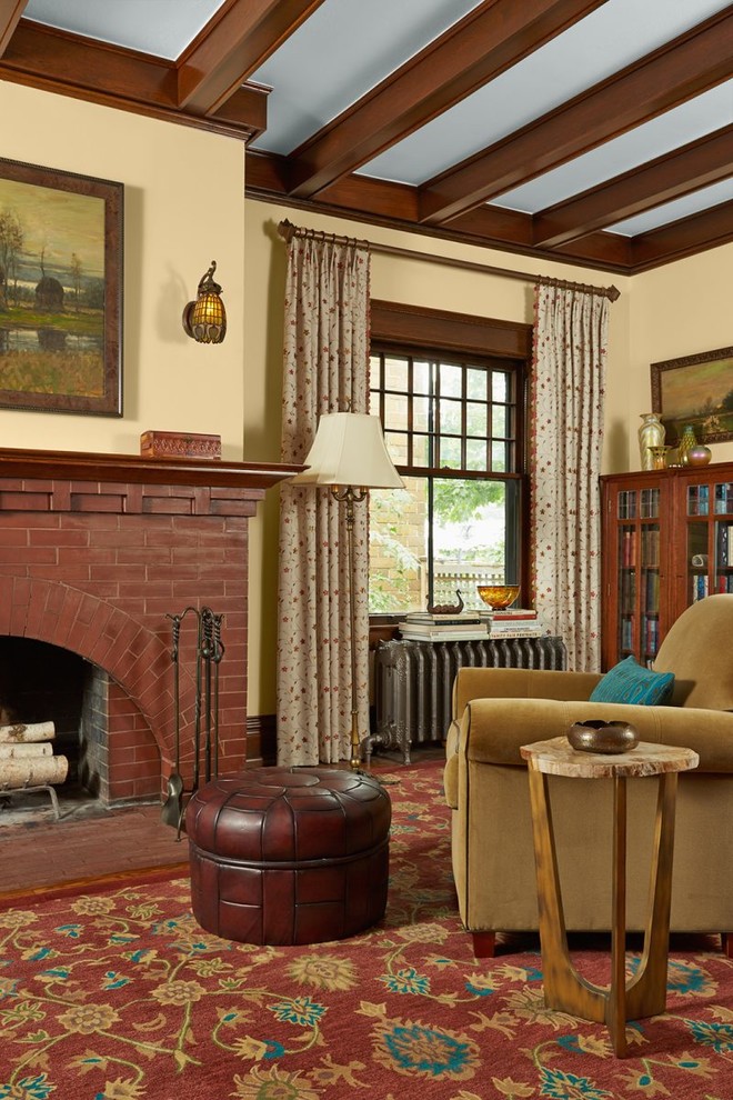Foto på ett amerikanskt vardagsrum, med beige väggar, en standard öppen spis, en spiselkrans i tegelsten och rött golv