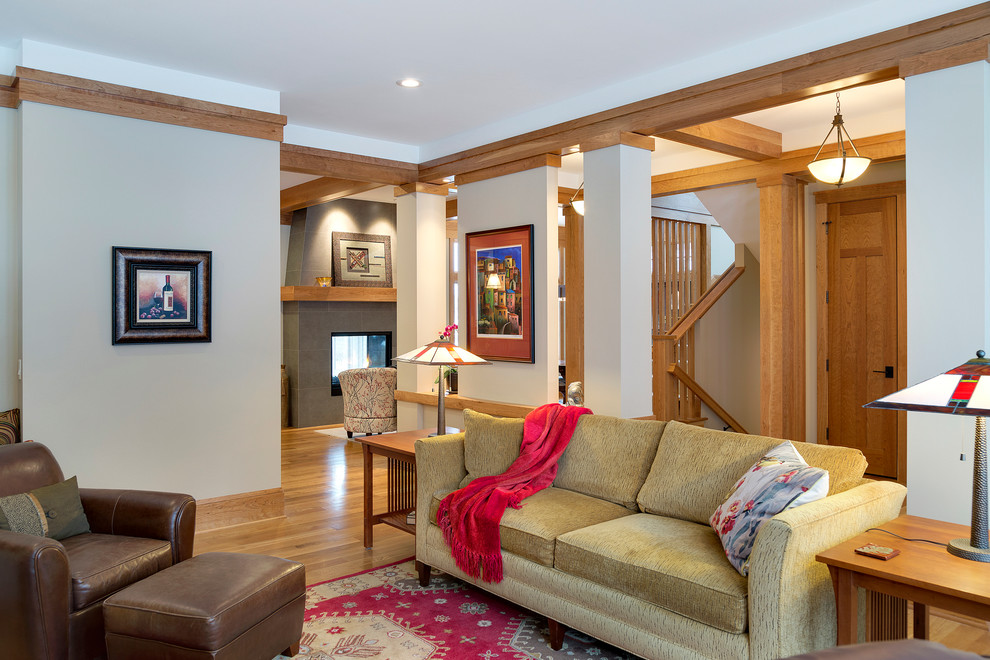 Exemple d'un grand salon chic ouvert avec un mur beige, un sol en bois brun, une cheminée standard, un manteau de cheminée en carrelage, une salle de réception et un téléviseur encastré.