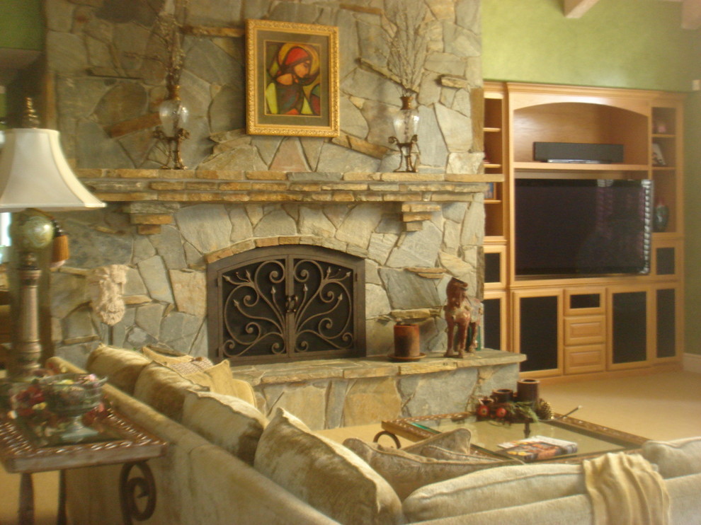 Immagine di un soggiorno tradizionale di medie dimensioni e chiuso con pareti verdi, moquette, camino classico, cornice del camino in pietra, parete attrezzata e pavimento beige