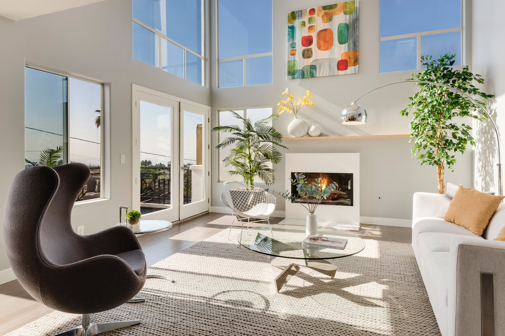Offenes Modernes Wohnzimmer mit grauer Wandfarbe, hellem Holzboden und Kamin in Los Angeles