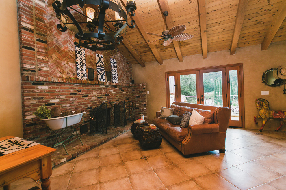 Пример оригинального дизайна: гостиная комната в стиле фьюжн с коричневыми стенами, полом из терракотовой плитки, печью-буржуйкой, фасадом камина из кирпича и коричневым полом