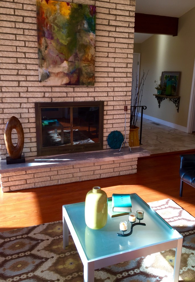 Photo of a large midcentury open plan living room in New York with white walls, medium hardwood flooring, a standard fireplace and a brick fireplace surround.