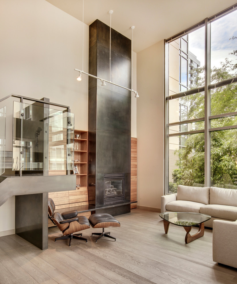 На фото: гостиная комната в стиле модернизм с светлым паркетным полом, стандартным камином, фасадом камина из металла и мультимедийным центром с