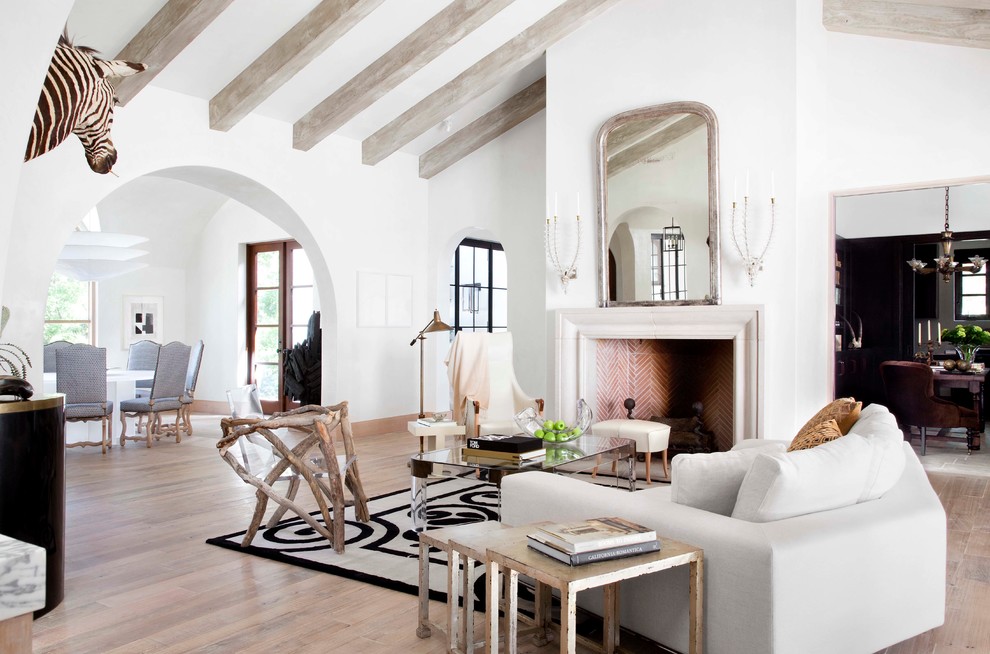 Ejemplo de salón mediterráneo con paredes blancas, suelo de madera en tonos medios y todas las chimeneas