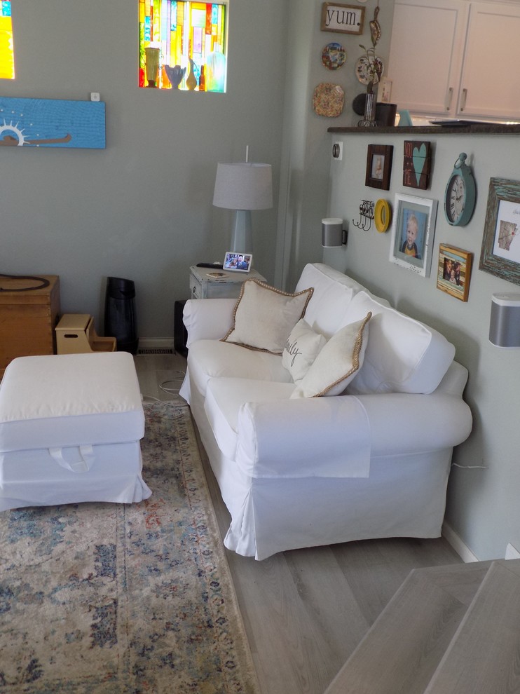 Idee per un piccolo soggiorno country aperto con pareti blu, pavimento in laminato, TV a parete e pavimento grigio