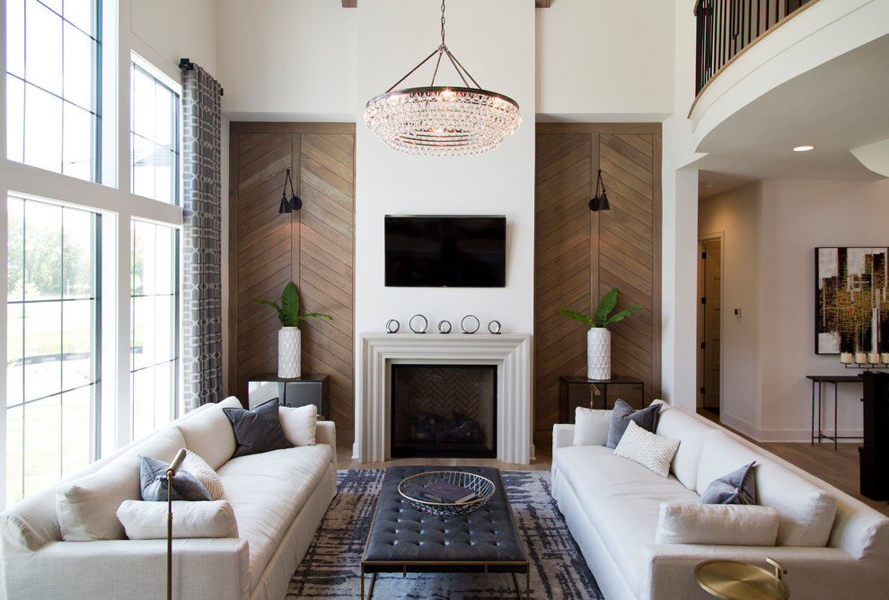 Стильный дизайн: большая открытая гостиная комната в стиле неоклассика (современная классика) с белыми стенами, стандартным камином, коричневым полом, светлым паркетным полом, фасадом камина из камня и телевизором на стене - последний тренд