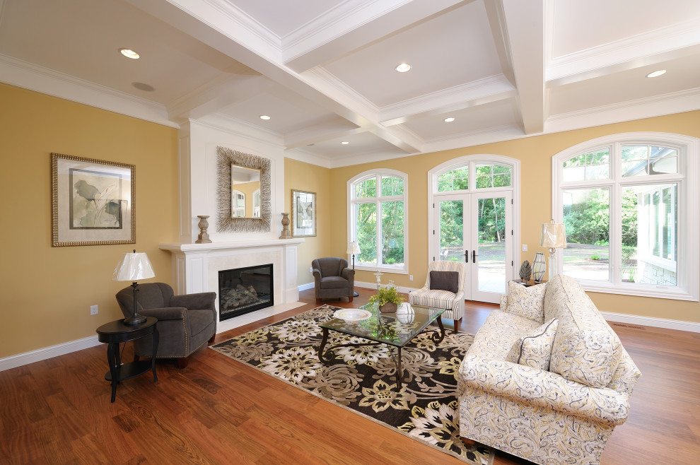 Traditional formal living room with yellow walls, medium hardwood flooring, a standard fireplace, a tiled fireplace surround and a coffered ceiling.