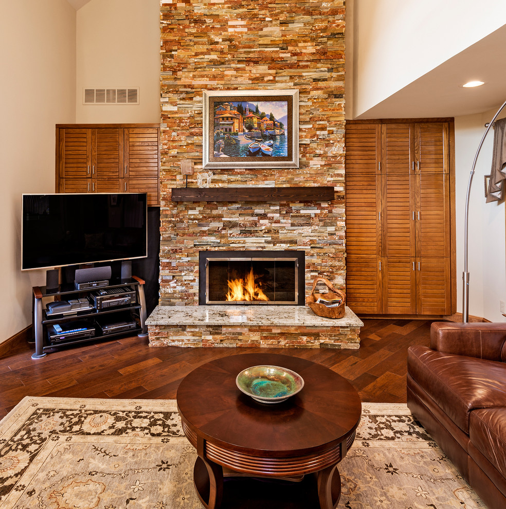 Cette image montre un salon traditionnel avec un mur beige, parquet foncé, une cheminée standard, un manteau de cheminée en pierre et un téléviseur indépendant.