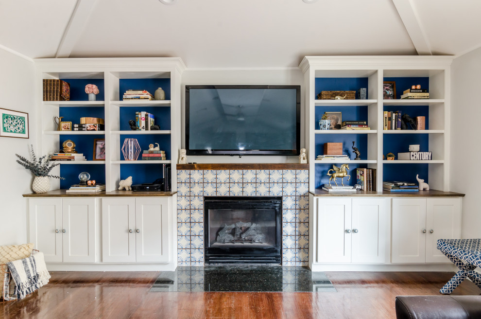 На фото: гостиная комната в современном стиле с серыми стенами, паркетным полом среднего тона, стандартным камином, фасадом камина из плитки, телевизором на стене и коричневым полом