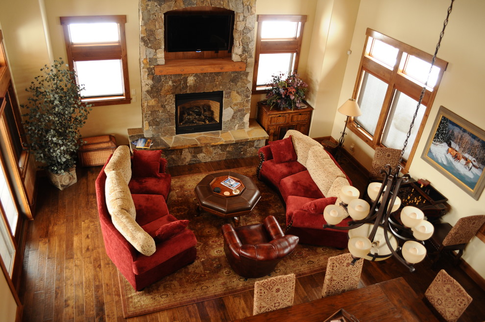 Inspiration for a rustic open concept dark wood floor living room remodel in Denver with beige walls, a standard fireplace, a stone fireplace and a media wall