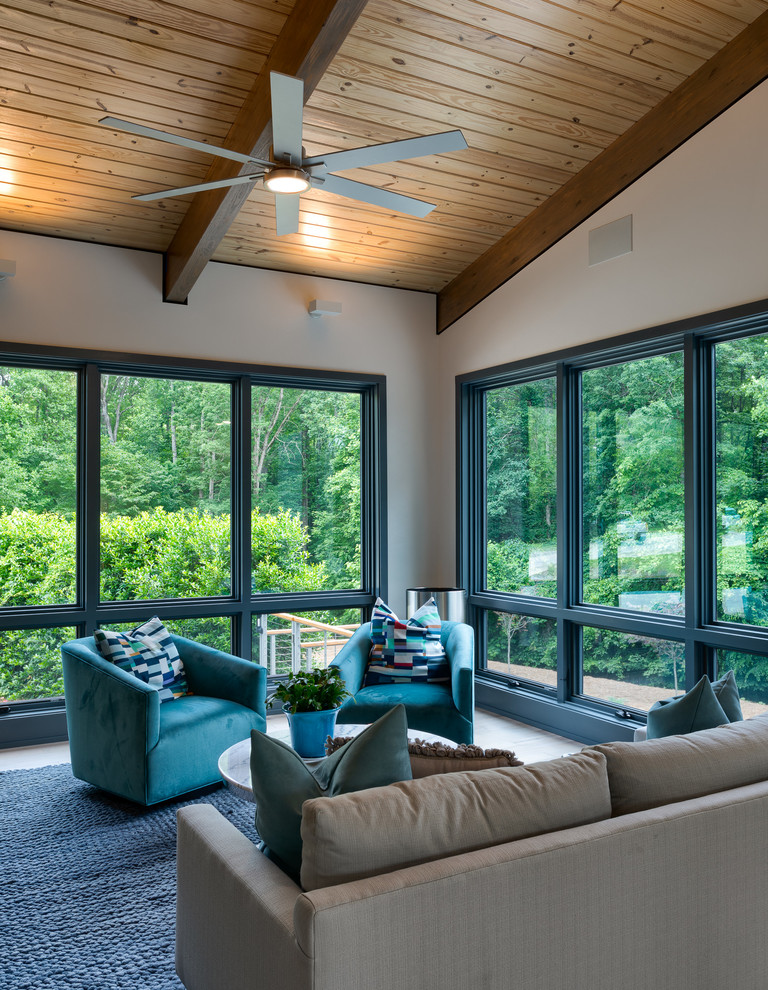 Medium sized beach style open plan games room in Charlotte with white walls, light hardwood flooring, a standard fireplace, a concrete fireplace surround, a wall mounted tv and grey floors.