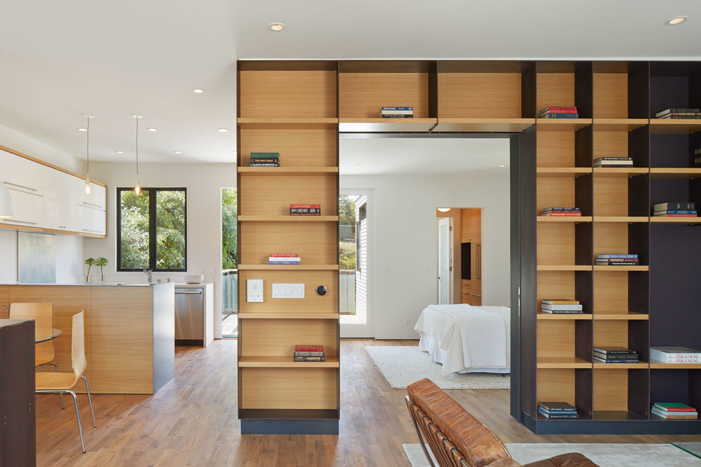Esempio di un piccolo soggiorno minimalista aperto con pareti bianche, pavimento in legno massello medio e parete attrezzata