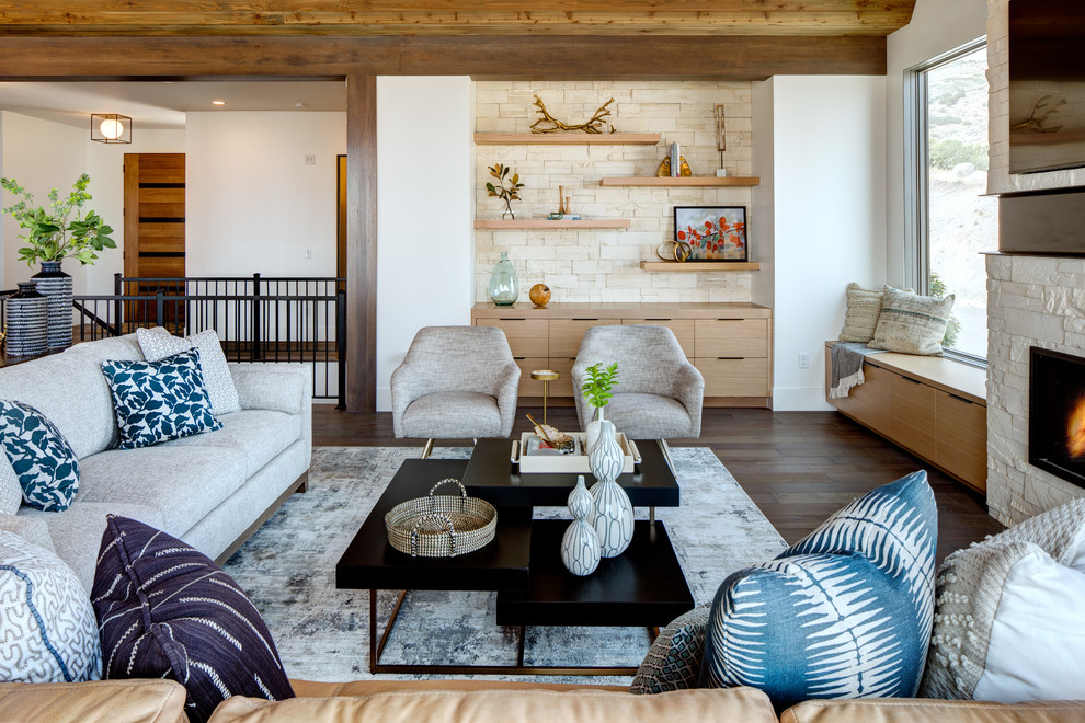 Cette image montre un grand salon design ouvert avec un mur blanc, un sol en bois brun, une cheminée standard, un manteau de cheminée en pierre, un téléviseur fixé au mur et un sol marron.