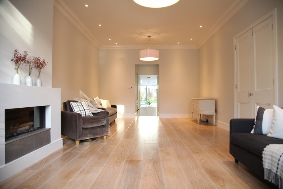 Photo of a medium sized contemporary formal enclosed living room in London with light hardwood flooring, a wood burning stove, grey walls, a plastered fireplace surround and a freestanding tv.