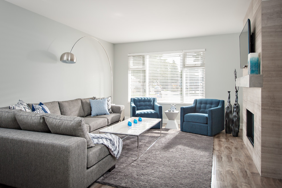Foto di un soggiorno classico di medie dimensioni e aperto con pareti grigie, pavimento in laminato, cornice del camino in pietra e TV a parete