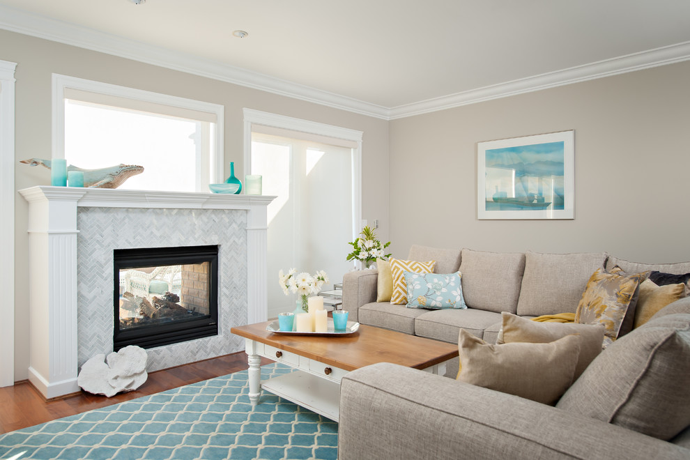 This is an example of a coastal open plan living room in Vancouver with a two-sided fireplace and a stone fireplace surround.
